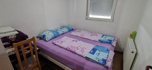 a small bedroom with a bed with purple sheets at Vikendica Lukavac in Lukavac