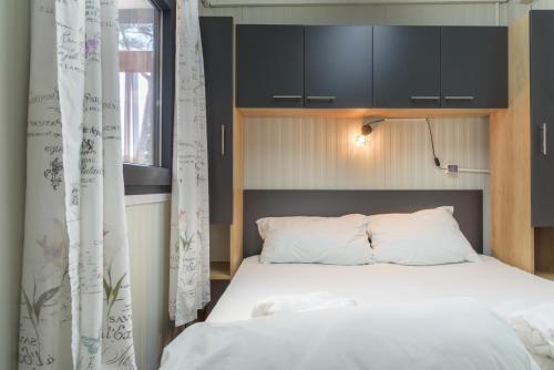 a bedroom with a white bed with black cabinets at Mobile Homes Camping Biograd in Biograd na Moru