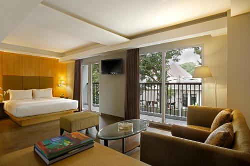 a hotel room with a bed and a living room at Hotel Santika Mataram in Mataram