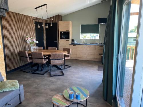 a kitchen and dining room with a table and chairs at Camping Kleine Belterwijde, Wiede Lodge met uitzicht over het water in Belt-Schutsloot