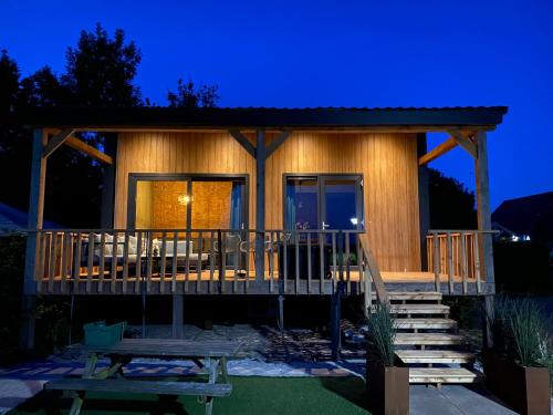 a log cabin with a deck at night at Camping Kleine Belterwijde, Wiede Lodge met uitzicht over het water in Belt-Schutsloot