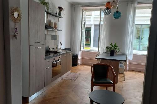 a kitchen with a table and a chair in a room at A 2 pas du marché in Saint-Jean-dʼAngély