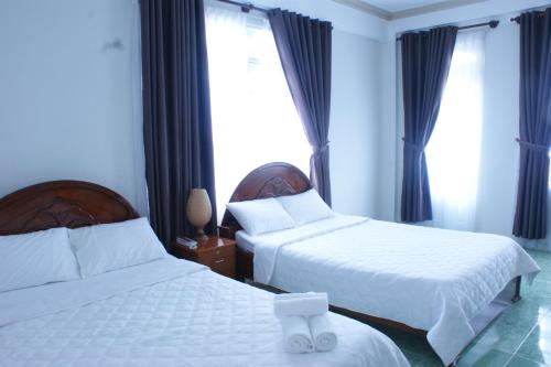 a hotel room with two beds and a window at Vuon Hoa Hong (Rosary) in Da Lat