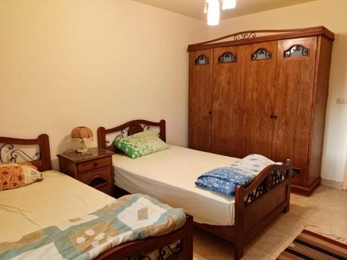 sypialnia z 2 łóżkami i drewnianą szafką w obiekcie Villa for Rent @ El Fanar Resort (Zaafarana-Sokhna) w mieście Ajn Suchna