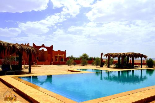 a large swimming pool with a building in the background at Kasbah Du Berger & Piscine in Merzouga