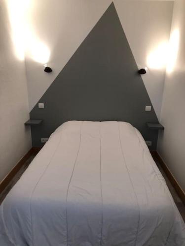 - une chambre avec un lit blanc et un mur noir dans l'établissement Appartement calme aigueblanche trois vallées, à Aigueblanche