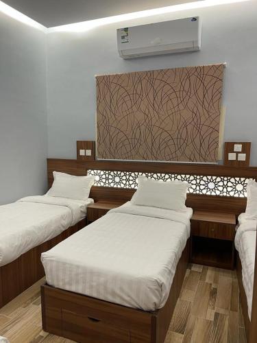 a room with three beds and a air conditioner at Aya Hostel in Al Madinah