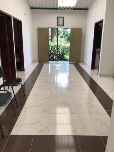 a hallway with a large tile floor with chairs and doors at Hermosa Finca de descanso en Villa Samaria a 35 minutos de Melgar in Melgar