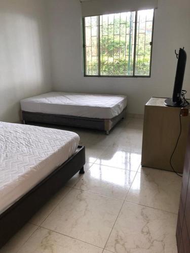 a room with two beds and a television in it at Hermosa Finca de descanso en Villa Samaria a 35 minutos de Melgar in Melgar
