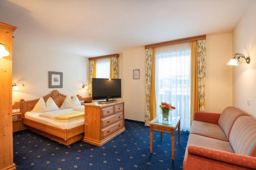 um quarto de hotel com uma cama e um sofá em Hotel Hammerwirt - Forellenhof em Untertauern