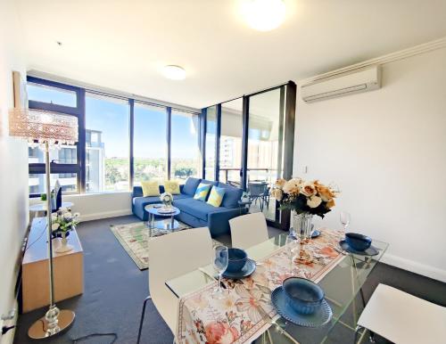 uma sala de estar com um sofá azul e mesas de vidro em Comfy & Bright 1 Bed Apt Olympic em Sydney