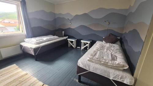 a room with two beds and a mountain mural on the wall at Lydersen Rorbuer Budget Hostel & Private Apartments in Fredvang