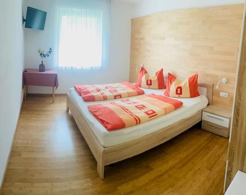 una camera da letto con un letto con cuscini rossi e arancioni di Alpenrose a Silandro