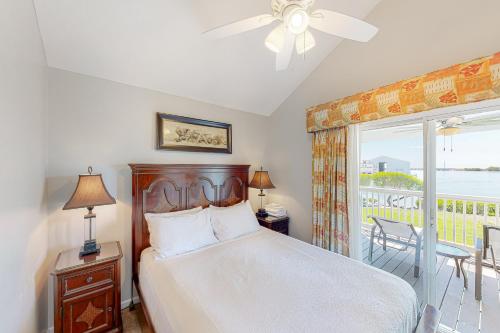 a bedroom with a bed with a ceiling fan and a balcony at C est la Vie in Duck Key