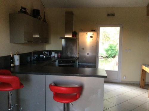 une cuisine avec un comptoir et deux tabourets rouges dans l'établissement Belle villa avec une piscine, à Clarensac