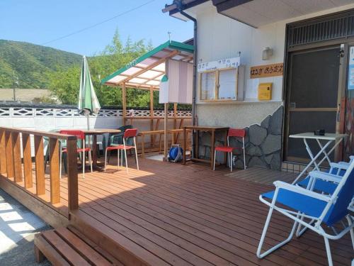 a wooden deck with chairs and a table and umbrella at 하루카오후나에 민숙 in Tsushima