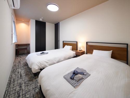 a hotel room with two beds with a cross on them at プライバシースイート伊豆高原 in Yawatano