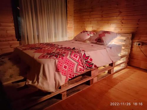 Cama en habitación de madera con suelo de madera en Cabana familiei, 