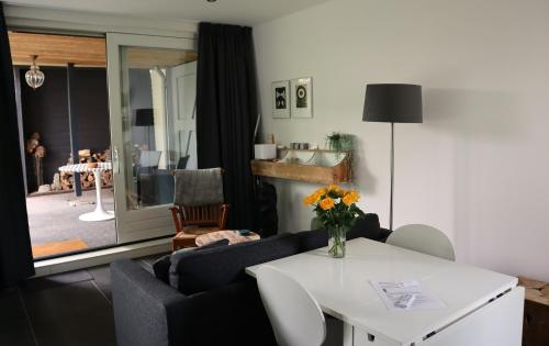 a living room with a couch and a table with flowers at B & B De Rode Beuk in Hilvarenbeek
