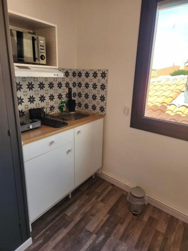 une petite cuisine avec un évier et une fenêtre dans l'établissement Chambre privée, à Chenac-sur-Gironde