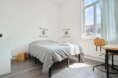 - une chambre blanche avec un lit et une fenêtre dans l'établissement Locations Tourcoing - Le Concorde, à Roubaix