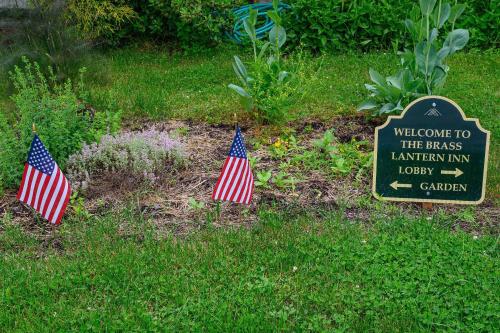 two american flags in the grass next to a sign at Brass Lantern Inn in Stowe