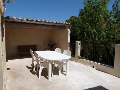 einen weißen Tisch und Stühle auf einer Terrasse in der Unterkunft La Remise in Le Cailar