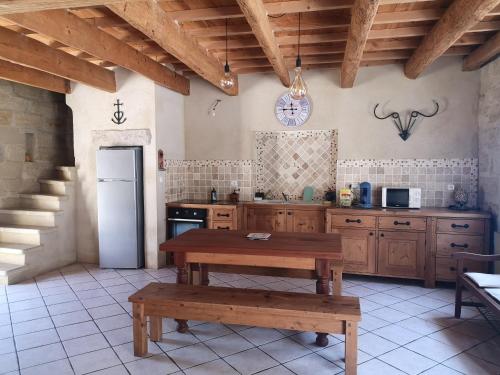eine Küche mit einem Tisch und einem Kühlschrank sowie einem Tisch und Bänken in der Unterkunft La Remise in Le Cailar