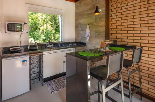 a kitchen with a sink and a counter with stools at Chalé Flores e Amores in Visconde De Maua