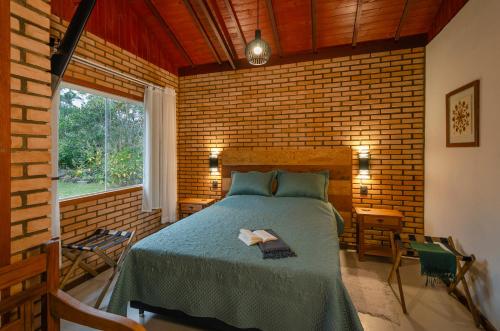 um quarto com uma cama e uma parede de tijolos em Chalé Flores e Amores em Visconde de Mauá