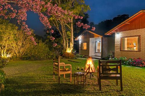 a yard with two chairs and a table with a fire at Chalé Flores e Amores in Visconde De Maua