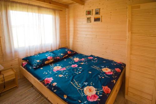 a bed in a wooden room with a blue comforter at Polna Przystań in Uherce Mineralne