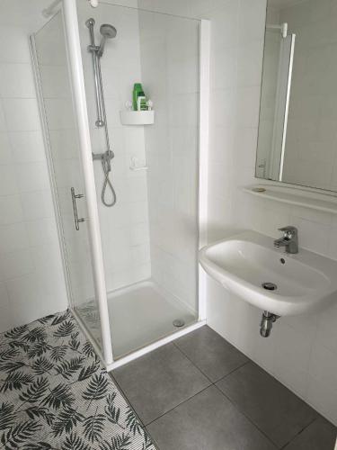 bagno bianco con doccia e lavandino di Chambre avec douche privé a Bruxelles