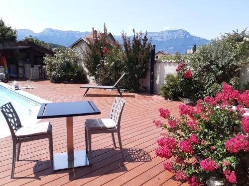 a patio with a table and two chairs and flowers at Un petit coin de paradis à Haute Jarrie in Jarrie