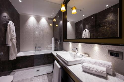 ein Badezimmer mit einem Waschbecken, einem Spiegel und einer Badewanne in der Unterkunft Palazzo Doglio in Cagliari