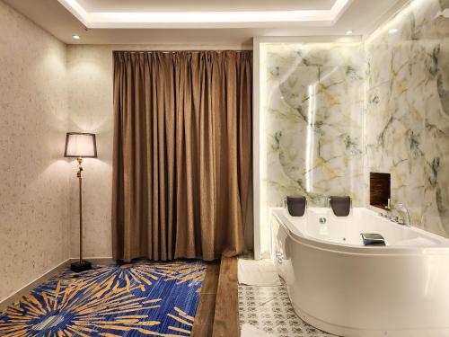 een badkamer met een groot bad in een kamer bij هوليداي الخليج الخبر Holiday Al Khaleej Hotel in Al Khobar