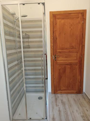 a shower with a glass door next to a wooden door at La Casa Di Lucia in San Vito Chietino