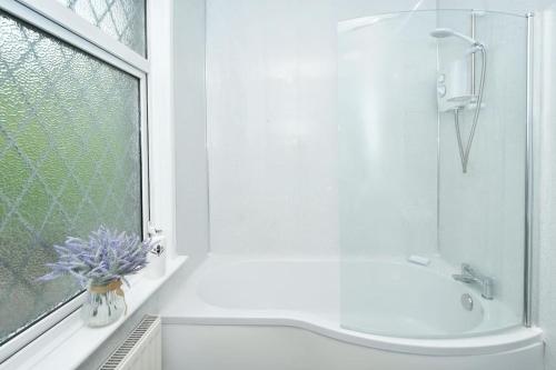 baño blanco con ducha y lavamanos en Frilsham House by YourStays, en Stoke on Trent