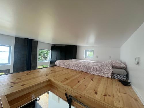 1 dormitorio con 1 cama y suelo de madera en Attefallshus på hornsudde, en Västervik