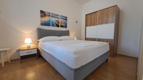 a bedroom with a large white bed and a lamp at Apartments Del Mare in Crikvenica