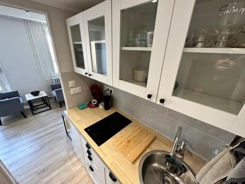 a kitchen with white cabinets and a sink at Cosy studio in Mulhouse