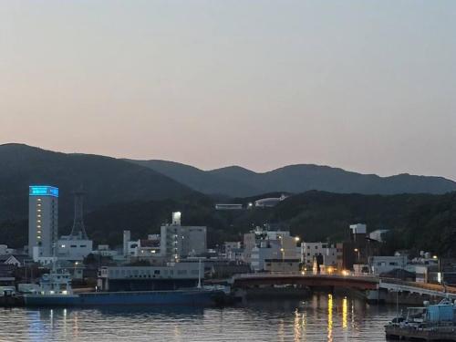 a city on the water with buildings and a bridge at 하루카오후나에 민숙 in Tsushima
