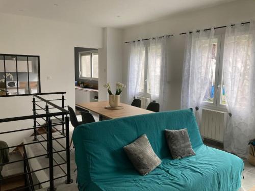 un salon avec un canapé bleu et une table dans l'établissement L’Atelier du Puits Volant, à Meximieux