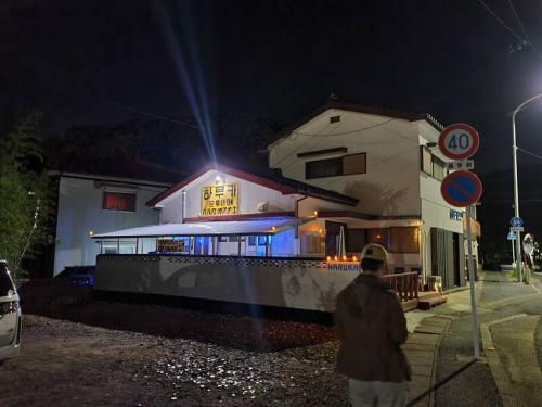 a person walking in front of a house at night at 하루카오후나에 민숙 in Tsushima