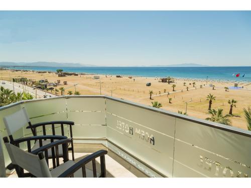 een balkon met 2 stoelen en uitzicht op het strand bij Acem Hotel in Ayvalık