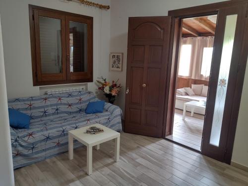 ein Wohnzimmer mit einem Bett, einem Tisch und einer Tür in der Unterkunft Casa Vacanze Villa Pomelia in Buonfornello