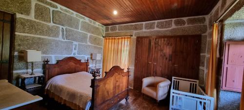 a bedroom with a bed and a chair in a room at Moradia no Gerês - O Africanista in Soengas