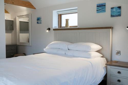 ein Schlafzimmer mit einem weißen Bett mit vier Kissen in der Unterkunft The Cow Shed - Rural Barn Conversion in Little Bytham