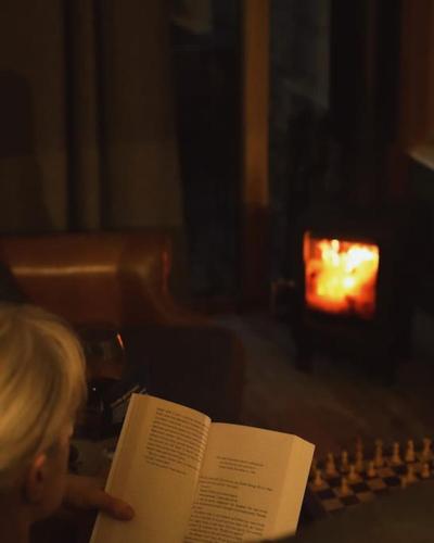 a little girl reading a book in front of a chessboard at The Cow Shed - Rural Barn Conversion with Hot Tub in Little Bytham