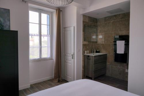 een badkamer met een bed, een wastafel en een raam bij Coeur de Provences in Saint-Didier